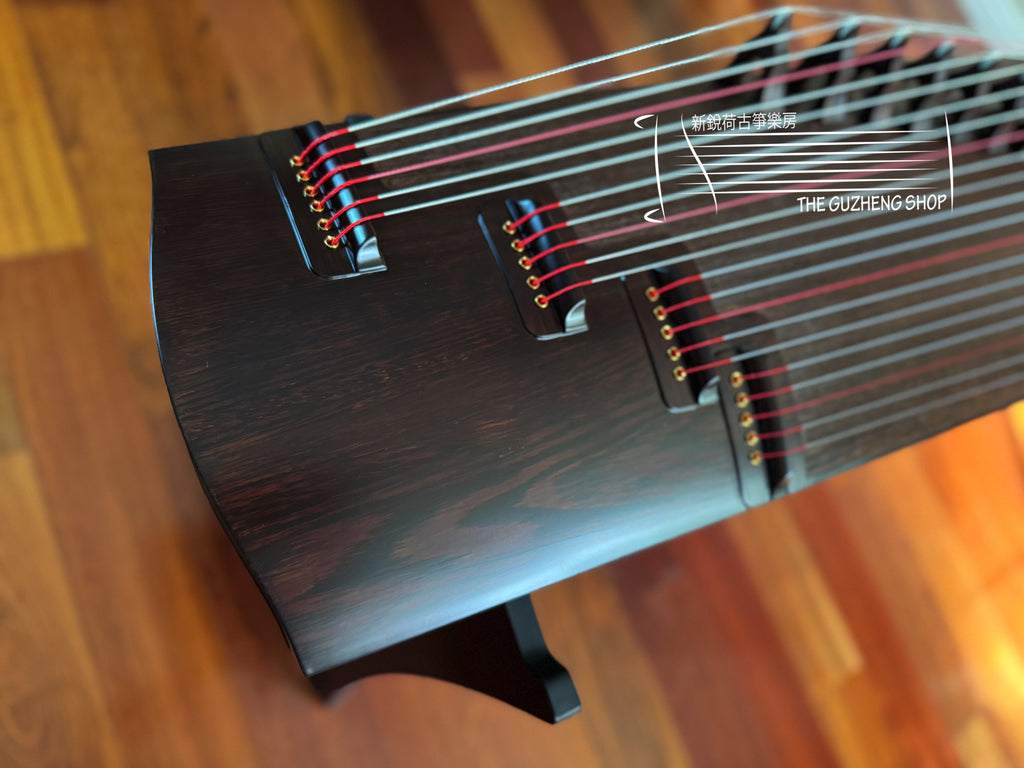 Close-up of a Guzheng on a wooden surface with 'The Guzheng Shop' branding.
