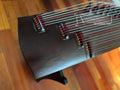 Close-up of a Guzheng on a wooden surface with 'The Guzheng Shop' branding.